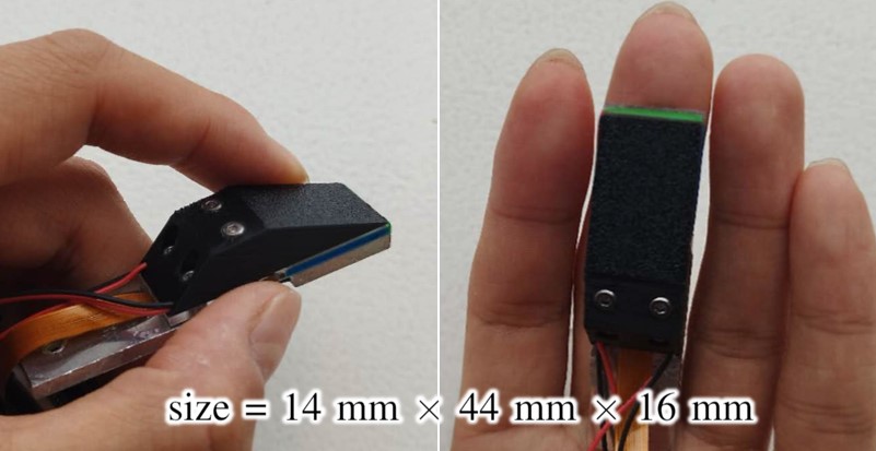 Miniature tactile sensor held between fingers, with dimensions of approximately 14 by 44 by 16 millimeters
